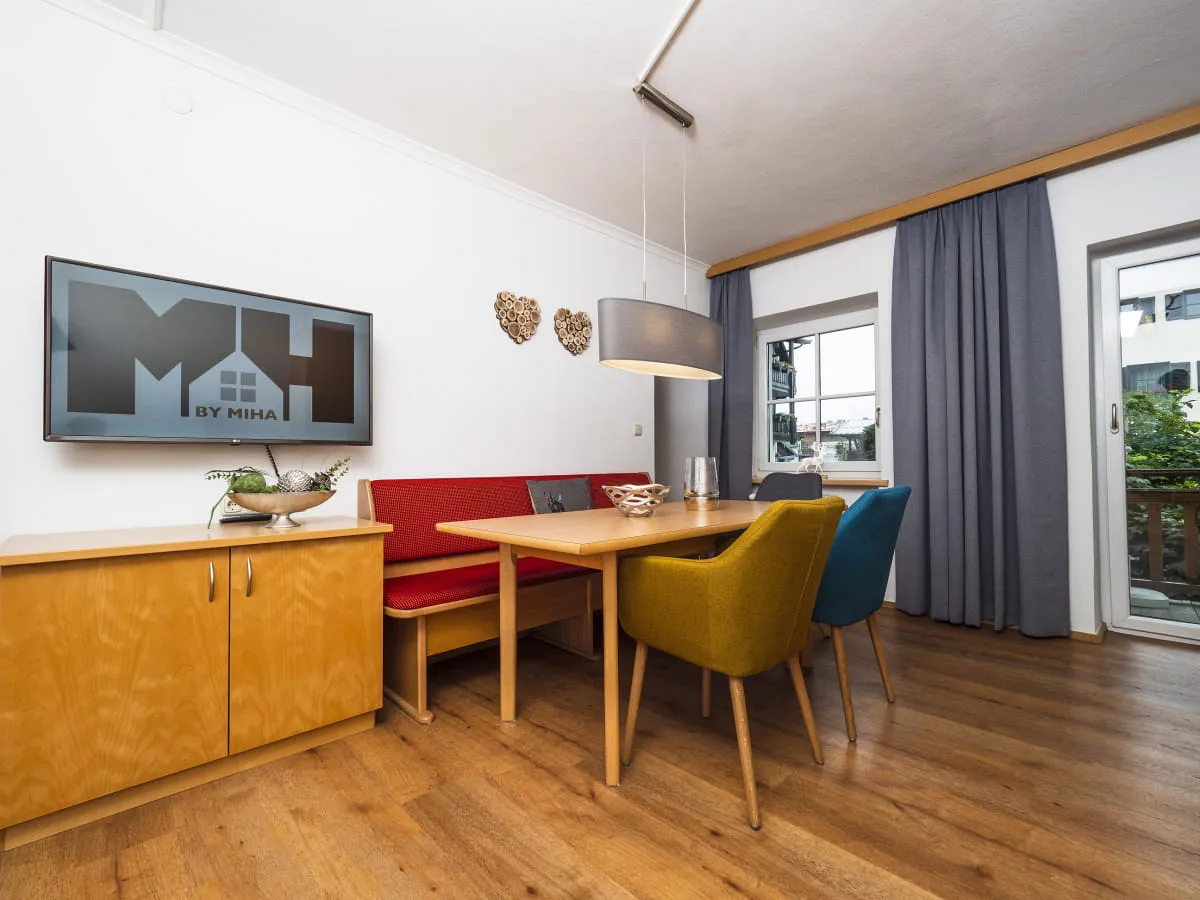 Moderne Wohnküche mit Tisch, Stühlen, Fernseher und Balkon.