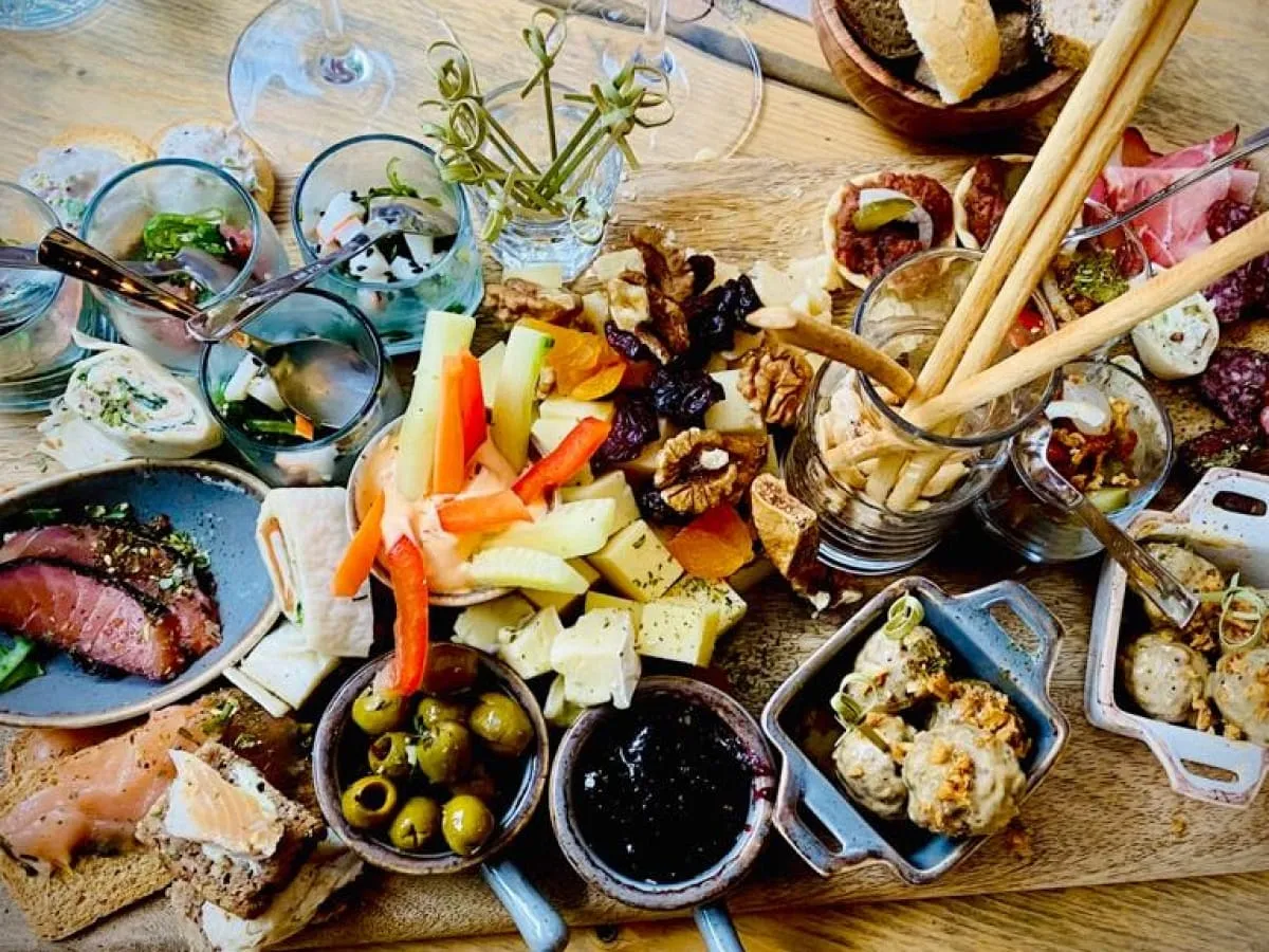 Platte mit Wurst, Käse, Gemüse, Oliven und Brot auf einem Holzbrett