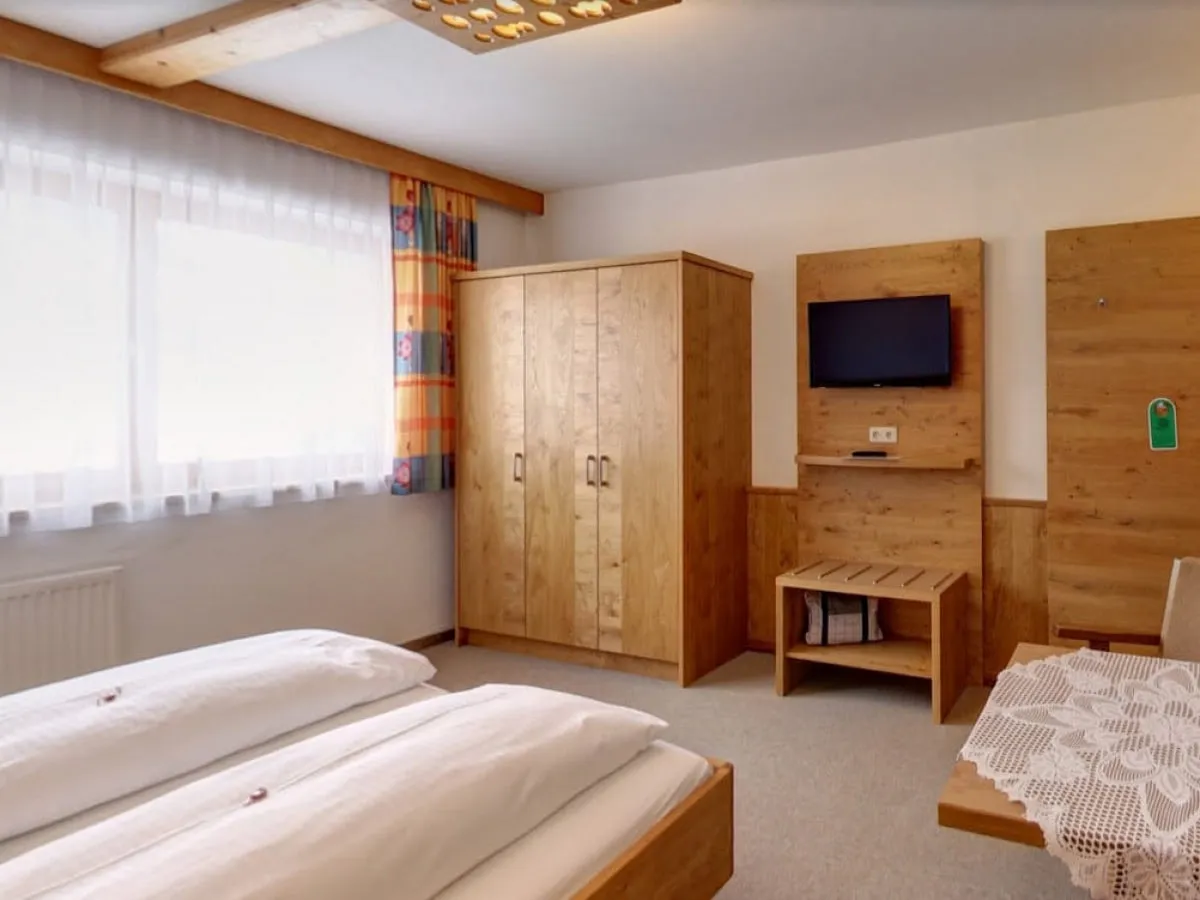 gemütliches Schlafzimmer mit zwei Betten, Holzmöbeln und Fernseher