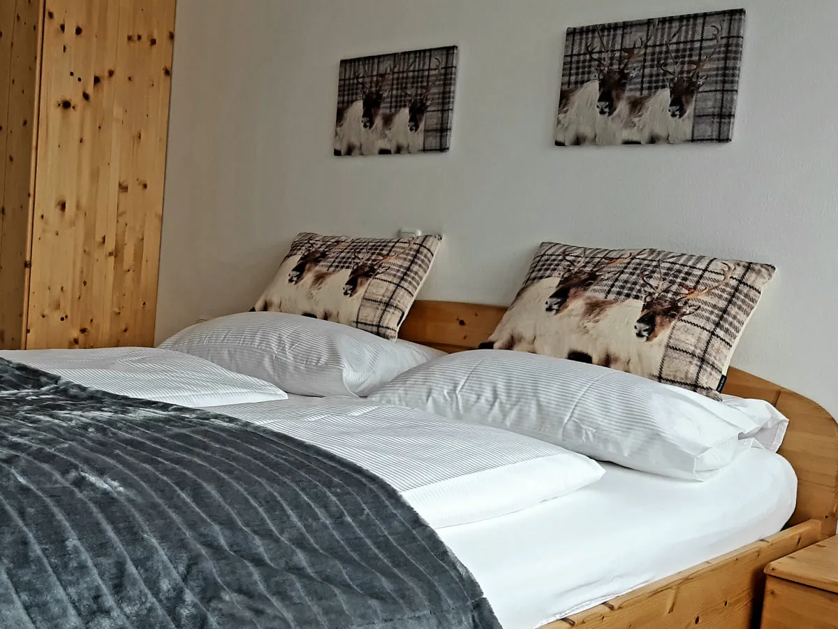 Schlafzimmer mit Holzmöbeln, Bettwäsche und zwei Wandbildern.