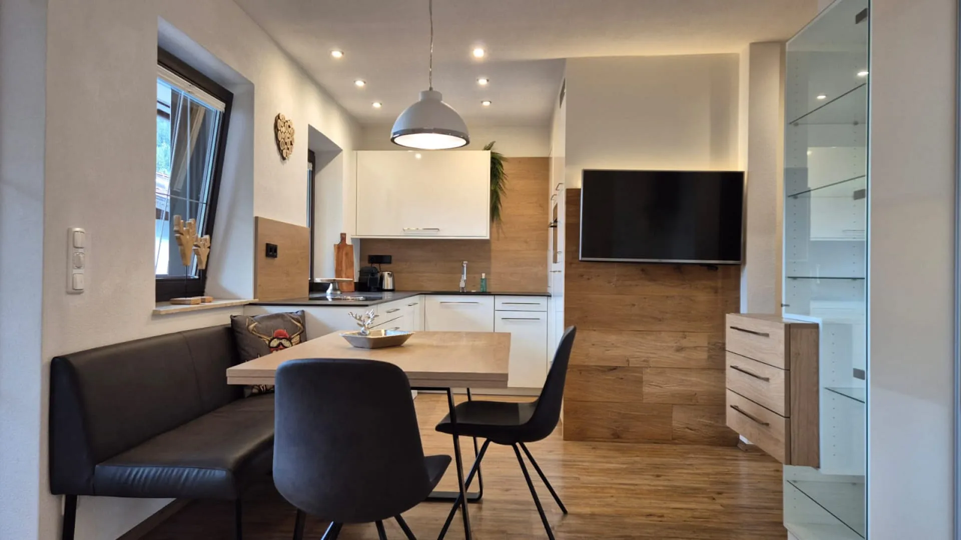 moderne Esszimmer mit Holzdetails, Tisch und Stühlen, angrenzende Küche